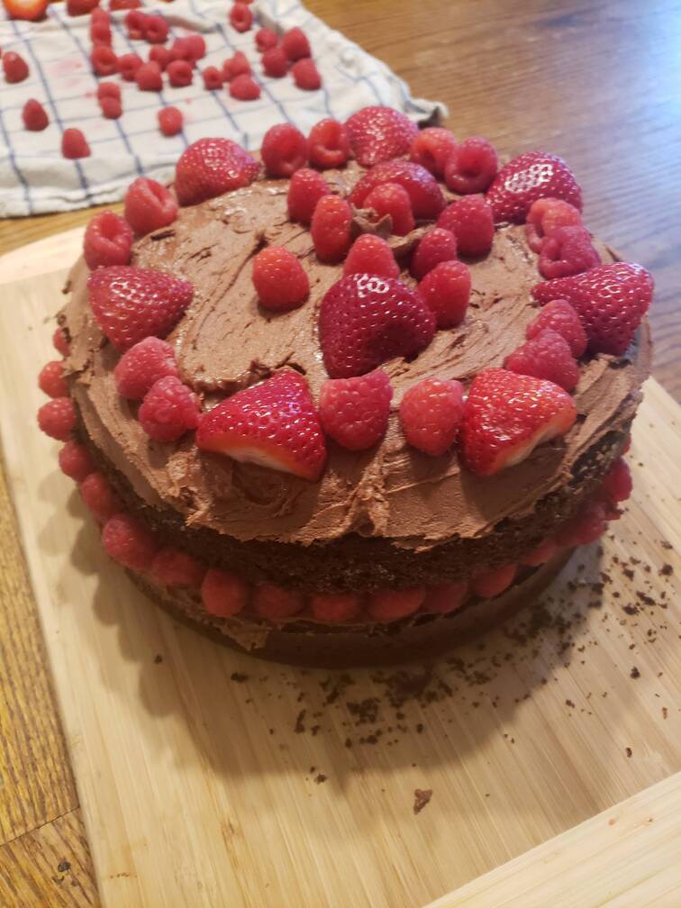 finished cake with chocolate frosting and fresh raspberries for toppings