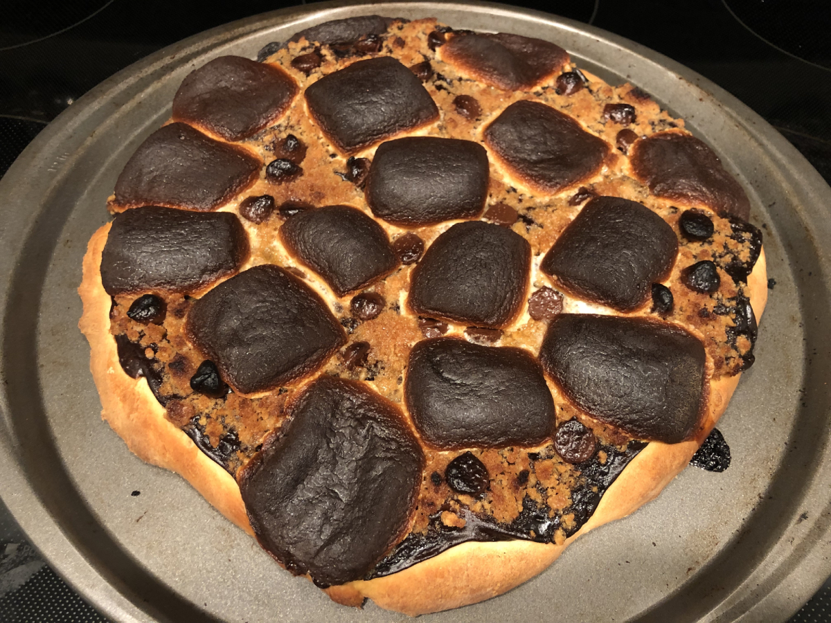 Baked s'mores pizza; graham has turned golden brown and marshmallows have a crispy outer coating