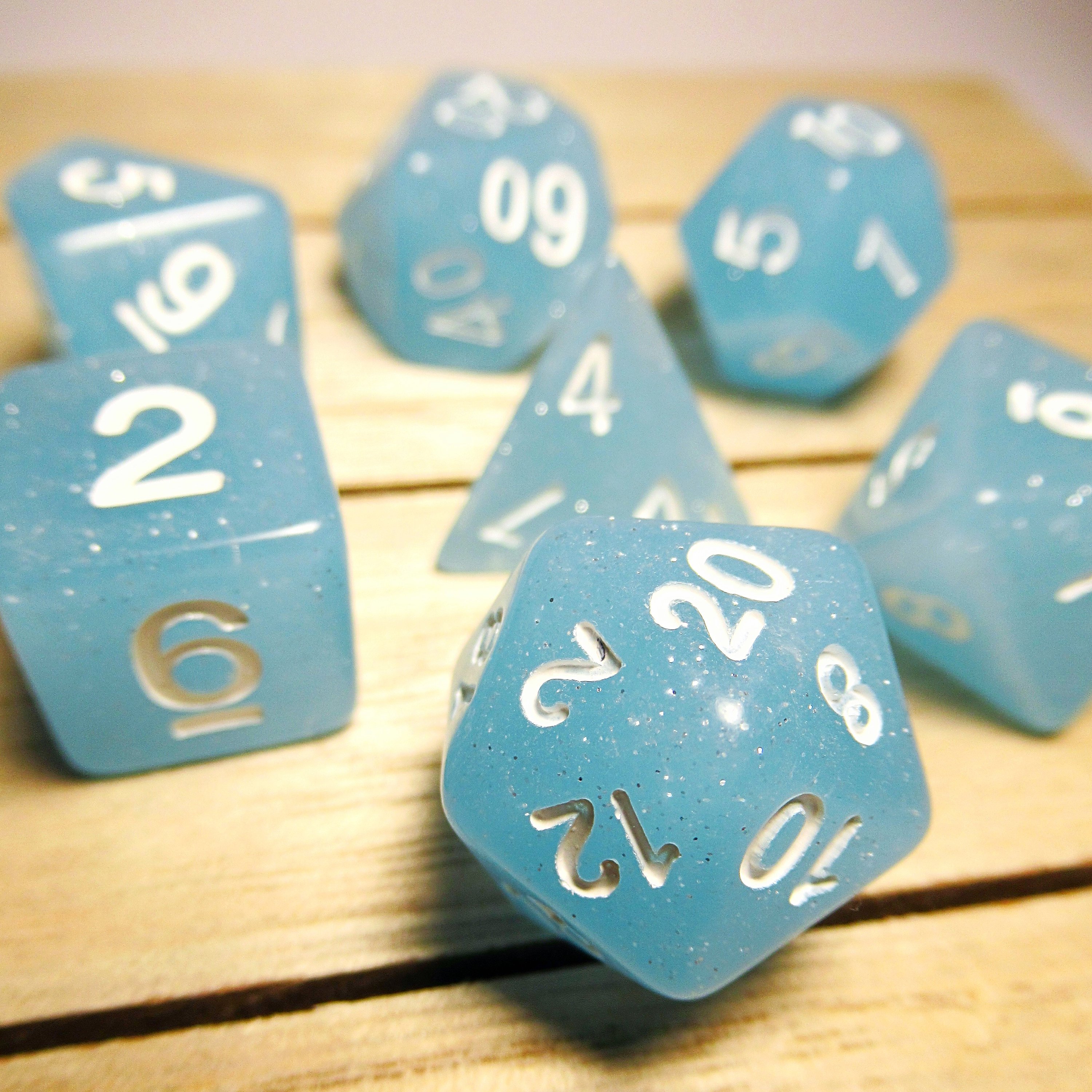 Translucent pale blue polyhedral dice with silver shimmers and white lettering.