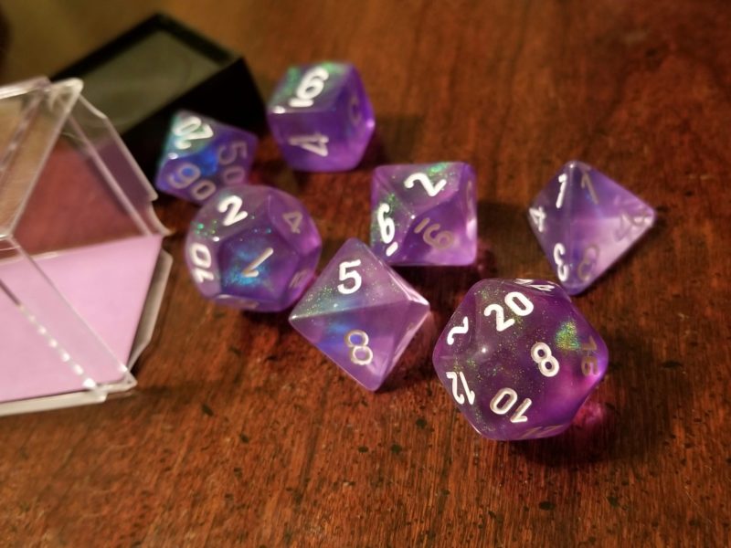 Translucent purple polyhedral dice with white numbers.