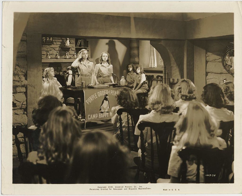 Still from the 1939 film The Under-Pup, showing a group of girls at camp holding a meeting of their club The Order of the Purple Penguins