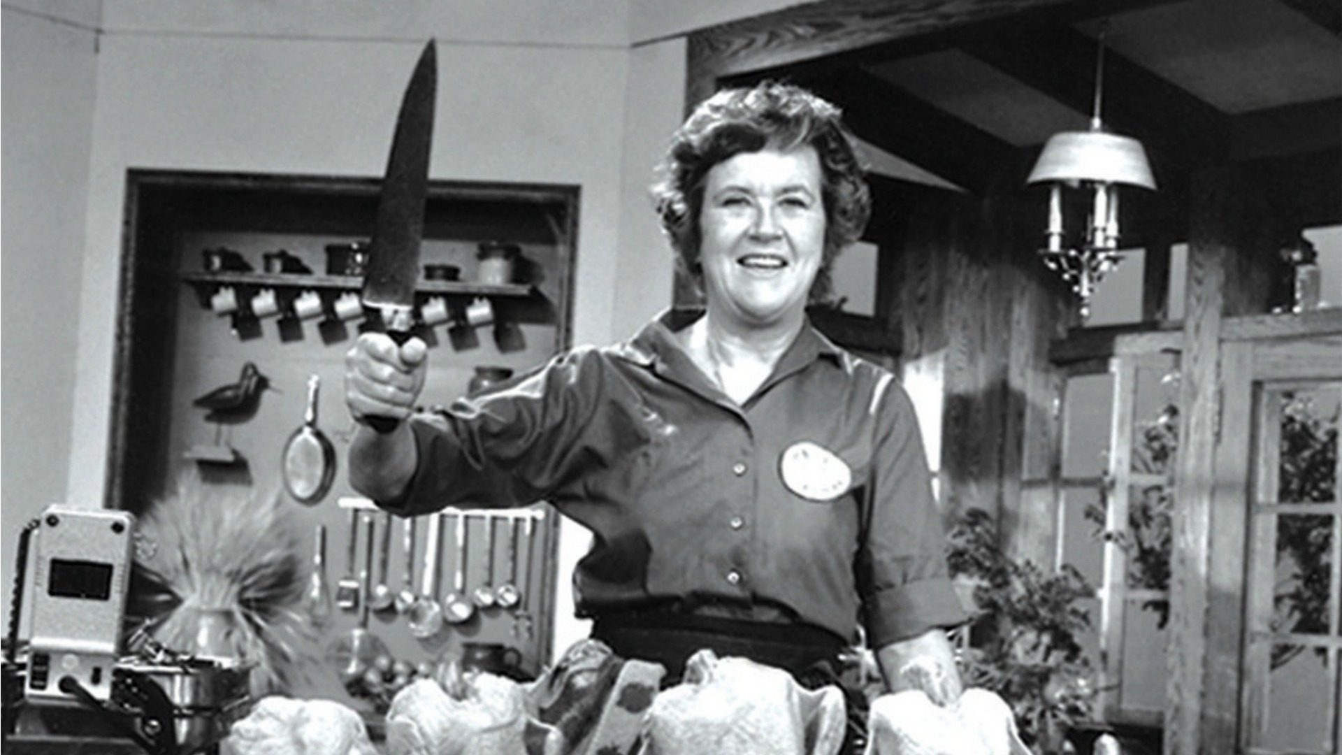 Julia Child, in the kitchen, holding a sharp knife.