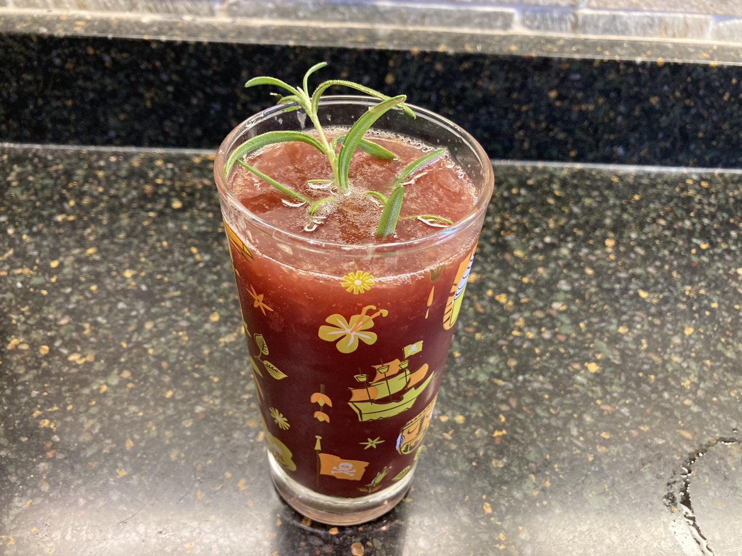 Full glass of juice and ginger ale mix with a sprig of fresh green rosemary sticking out of the center