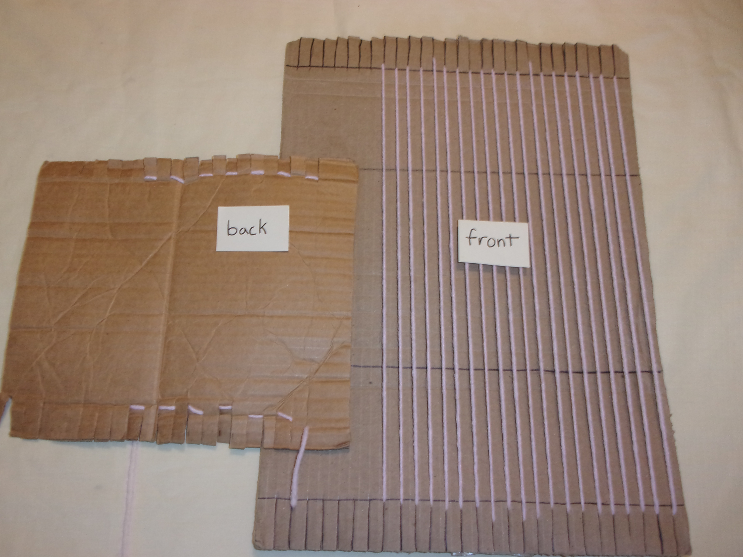 Two cardboard looms, one showing the front and the other showing the back. The front side has all of the visible yarn
