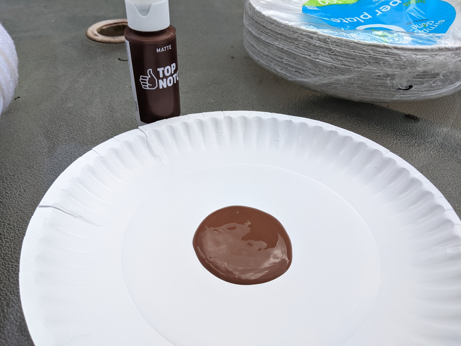 A dollop of brown paint in the center of a paper plate