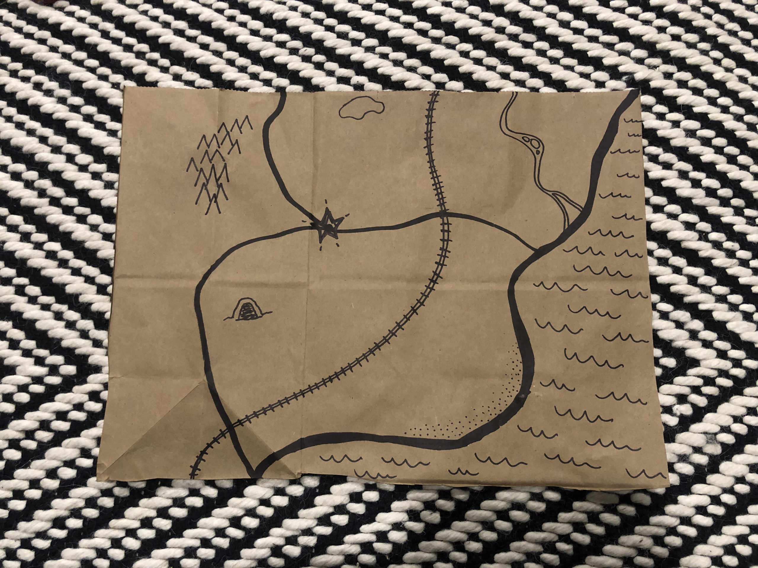 a map drawn in black marker on a brown paper bag with geographical elements drawn in according to the descriptions above