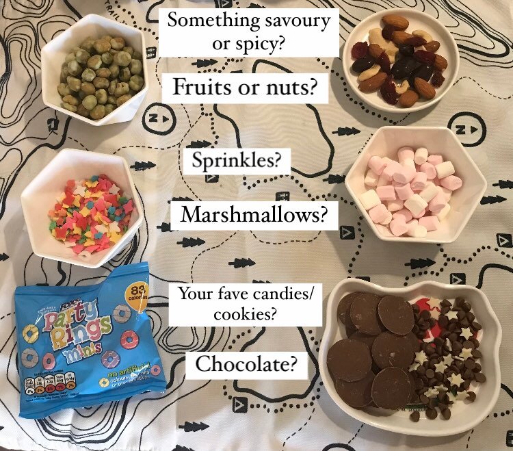 An array of small bowls including salty nuts, trail mix, marshmallows, chocolate pieces, sprinkles/jimmies/hundreds and thousands (depending on your locale), and "party rings" which seem to be a colorful British treat in a blue bag