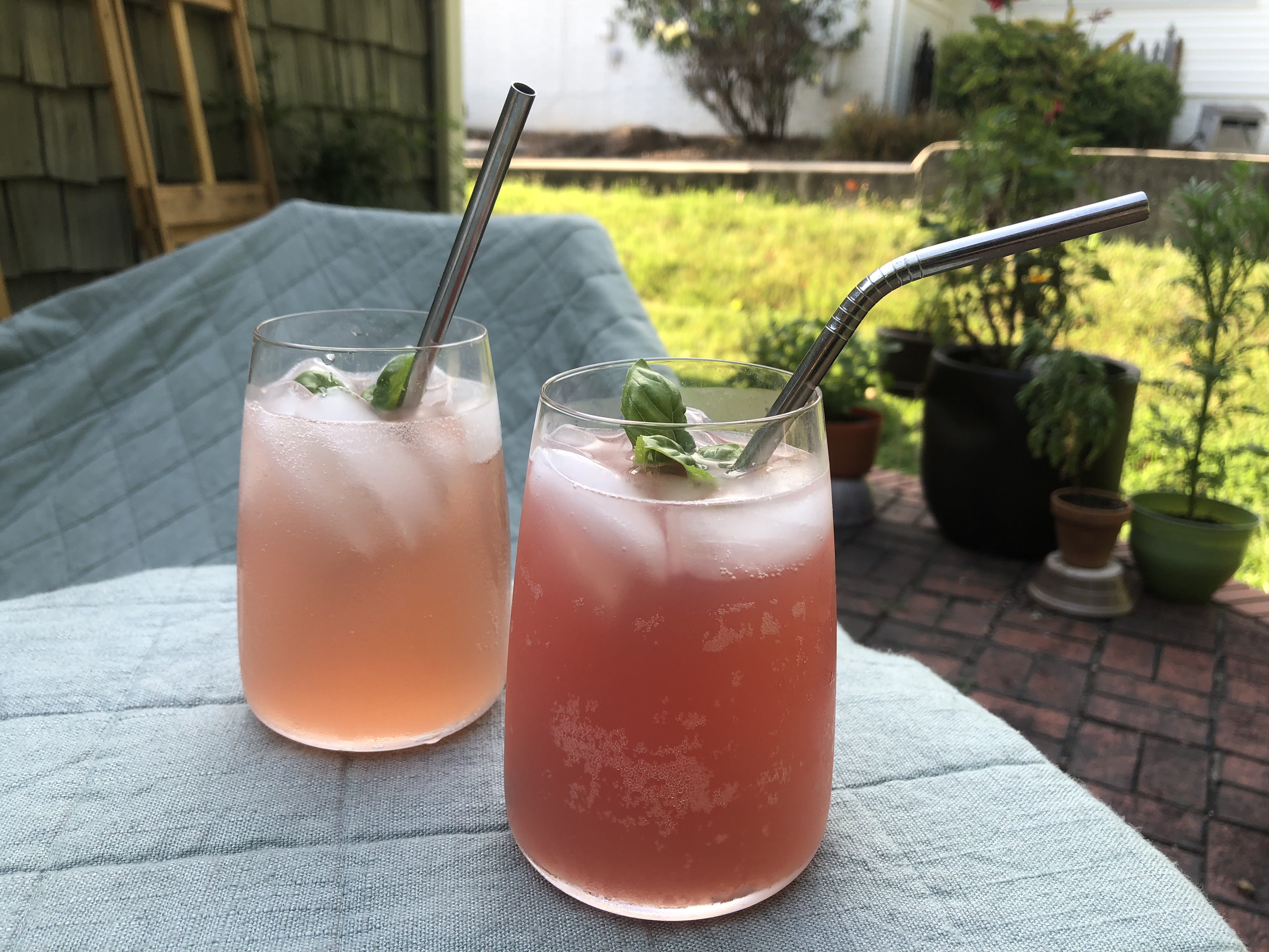 two drinks that are different shades of pink with metal straws