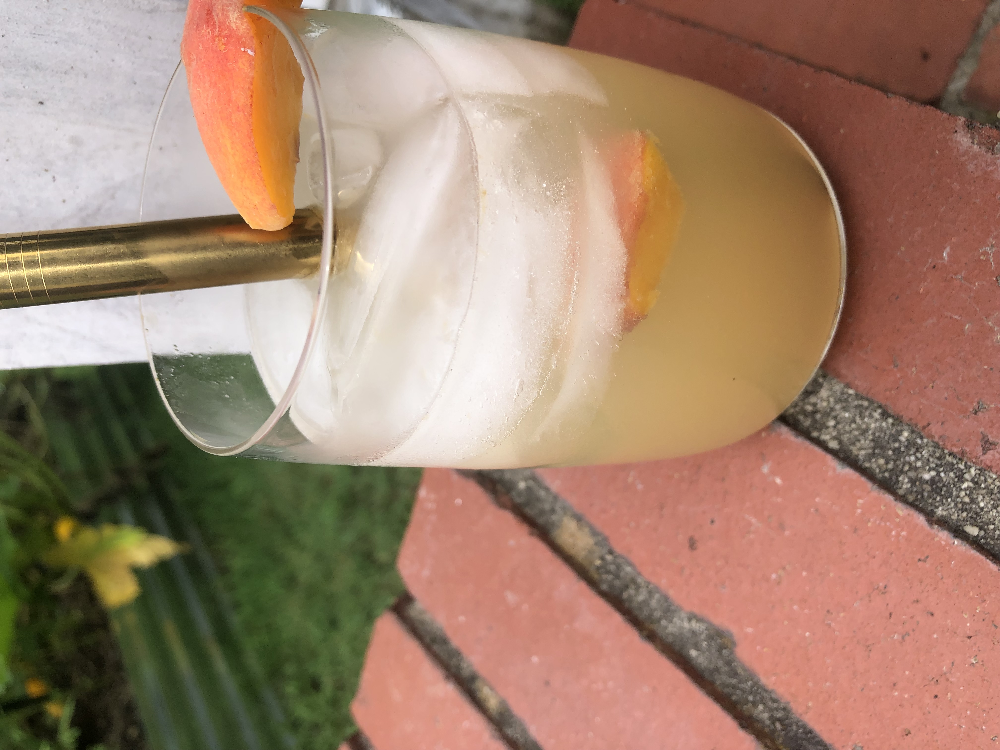 side view of an orange drink with an orange slice garnish and a gold straw