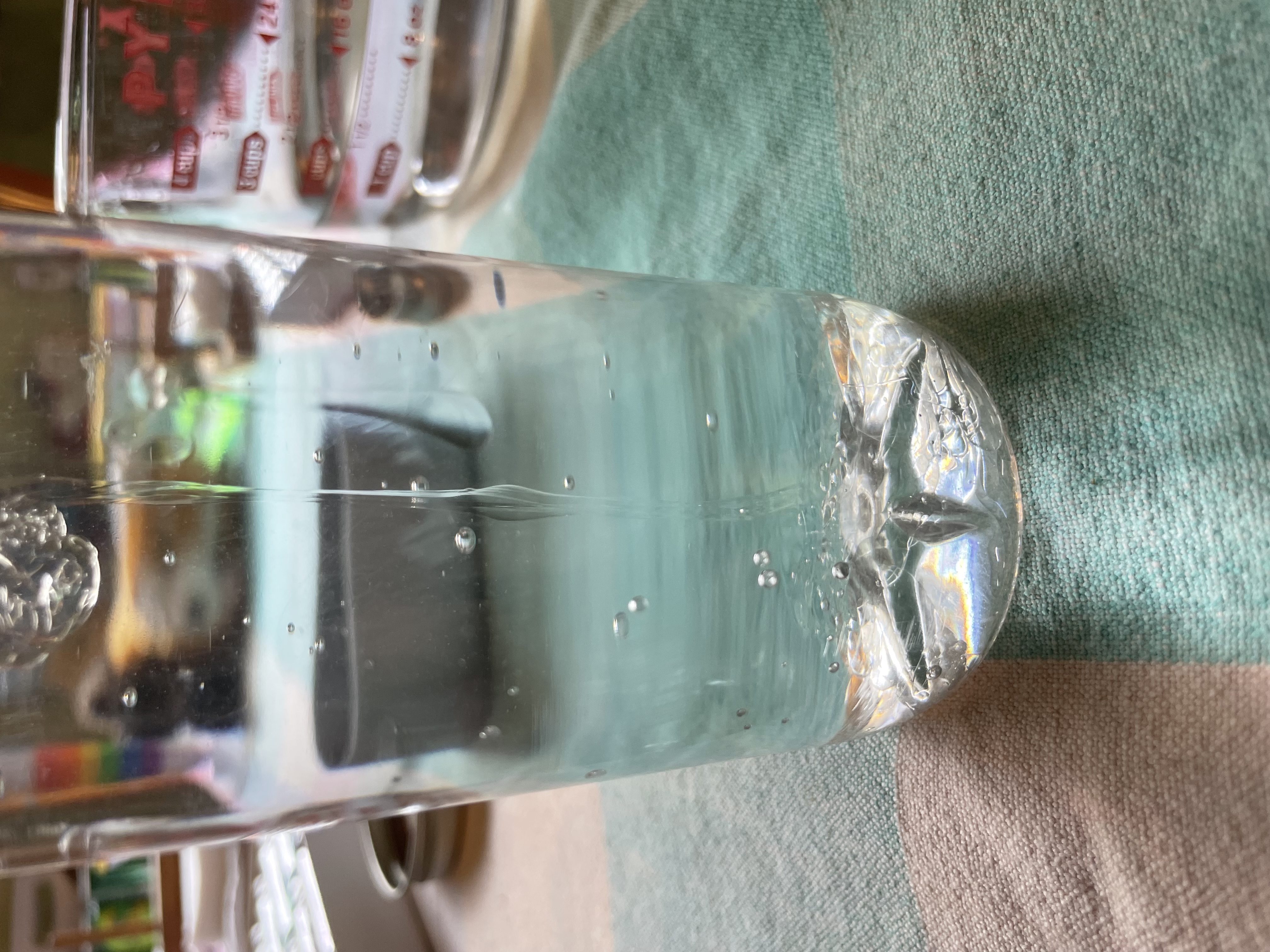 a clear bottle filled with water; a stream of clear glue is flowing into it