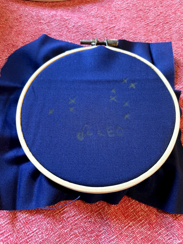 blue fabric is stretched inside an embroidery hoop