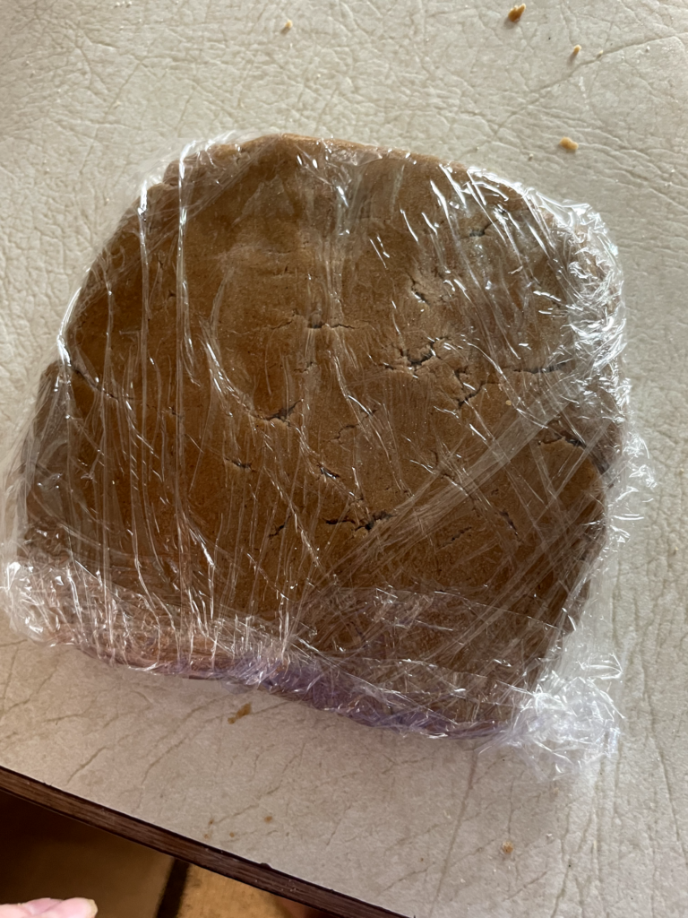 brown dough is wrapped in clear cling wrap