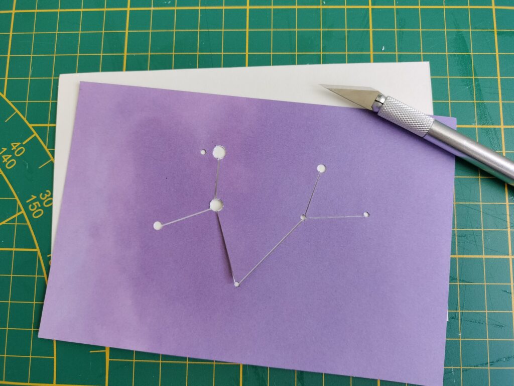 thread is laced through the holes on the purple piece of cardstock