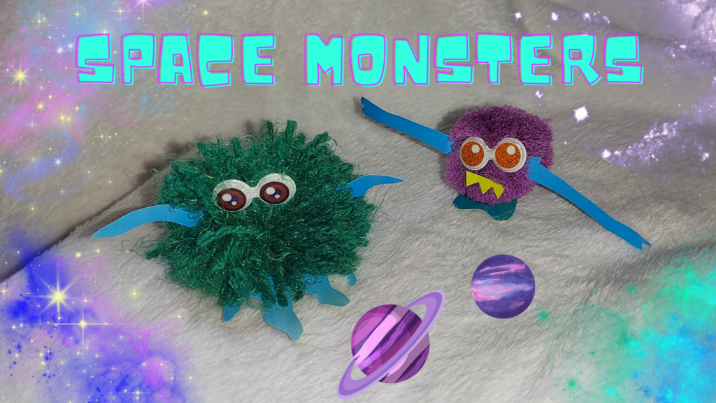 a completed green pompom monster and purple pompom monster on a starry background