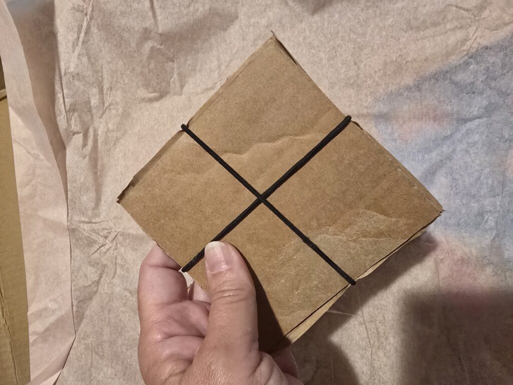 the squares are all stacked together with the cardboard on the outside; rubber bands hold the packet together in an X shape