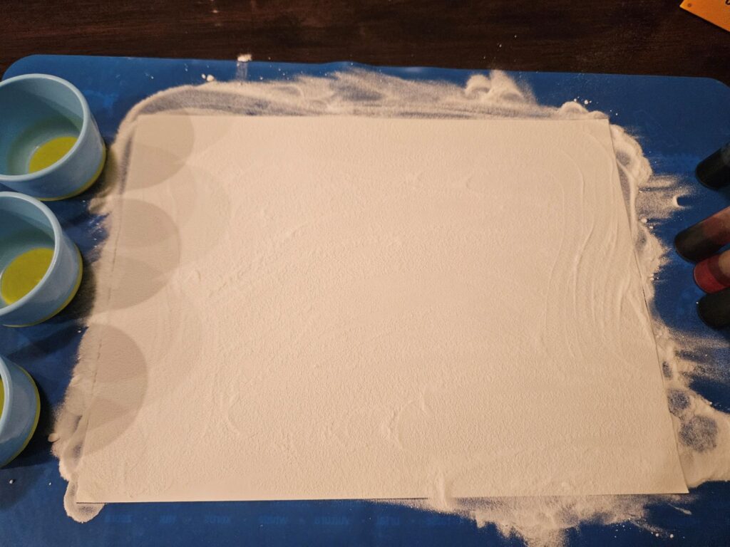 a piece of paper with an even layer of fine, white "sand-like" baking soda on it